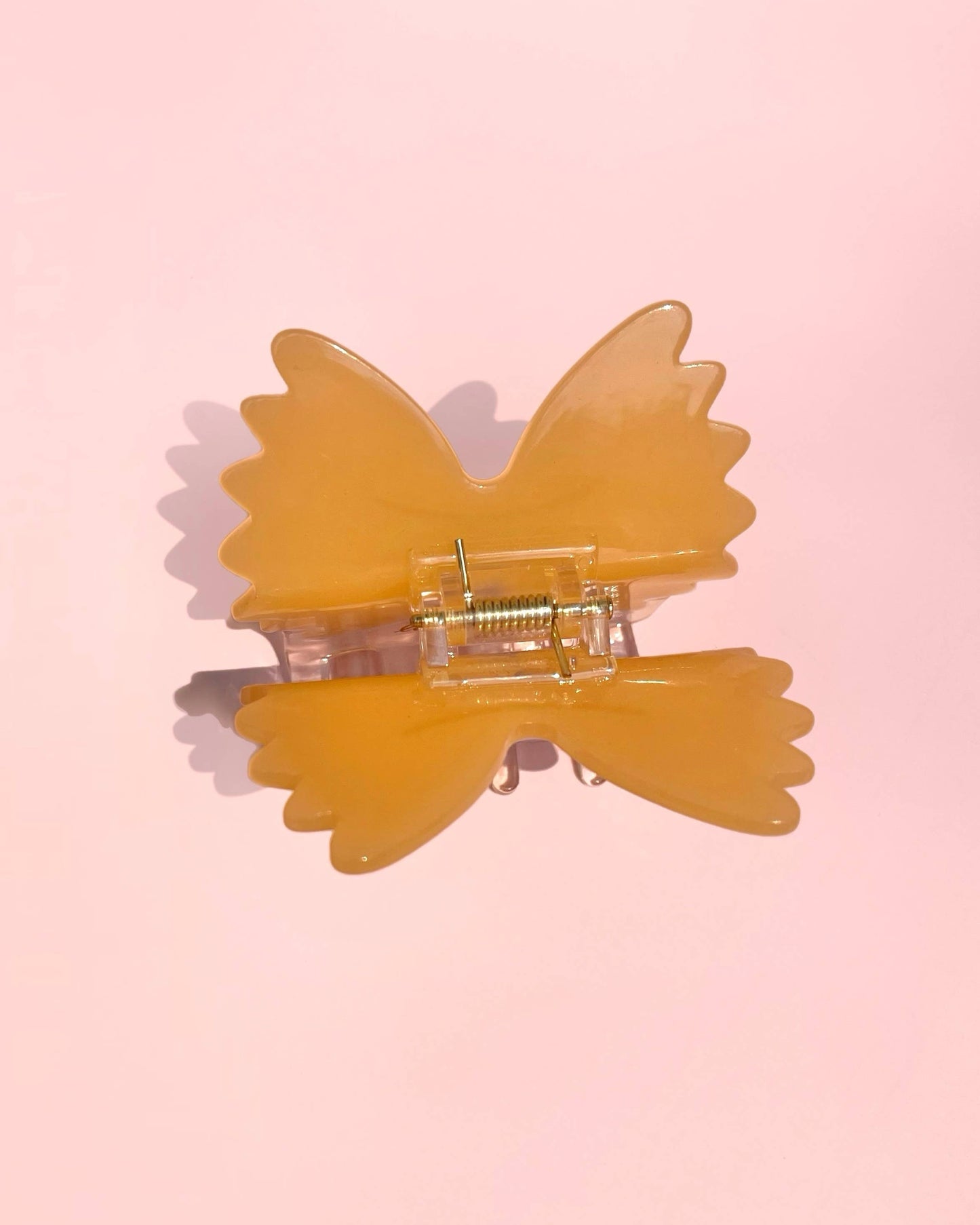 Yellow butterfly-shaped hair clip on a pink background