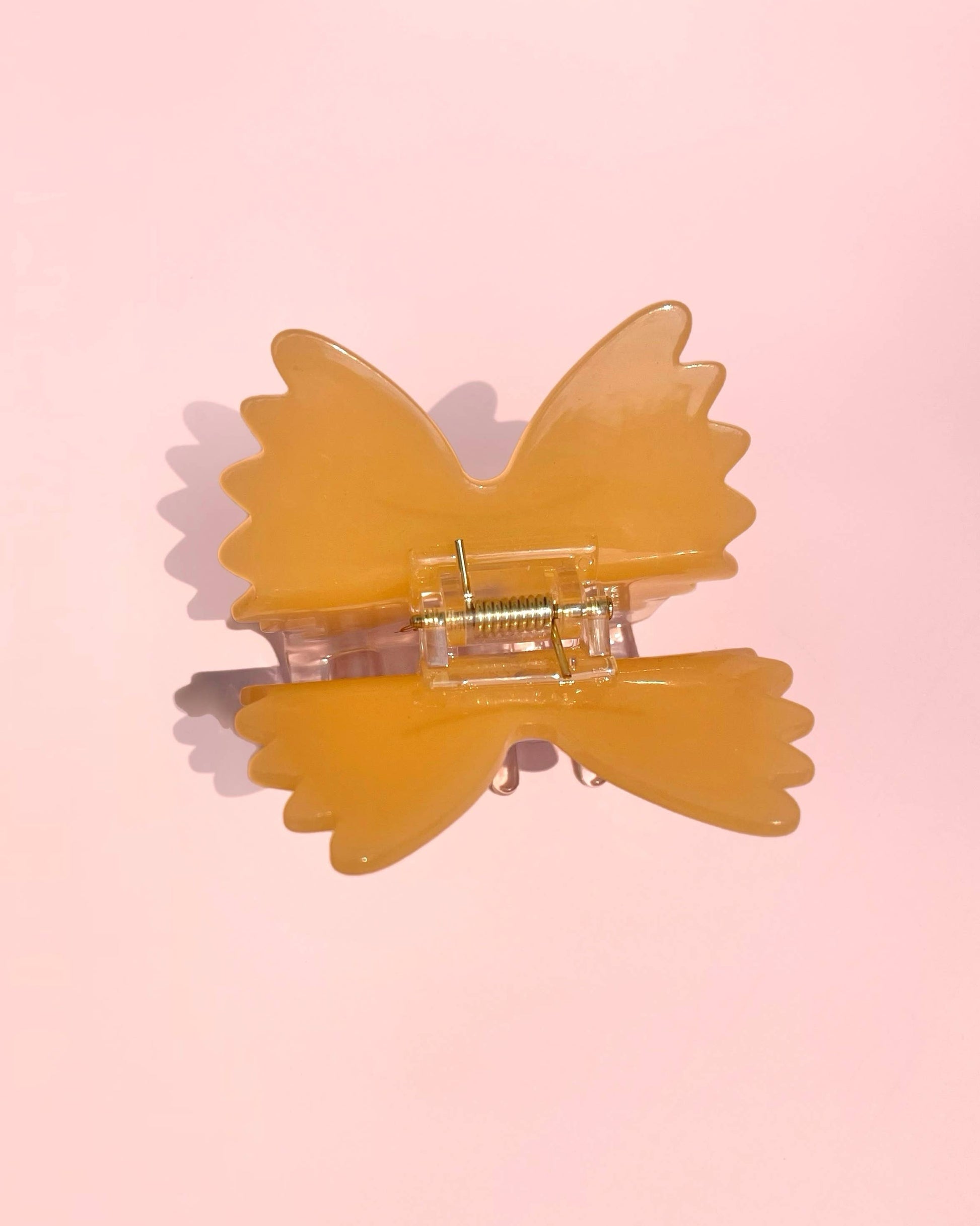 Yellow butterfly-shaped hair clip on a pink background