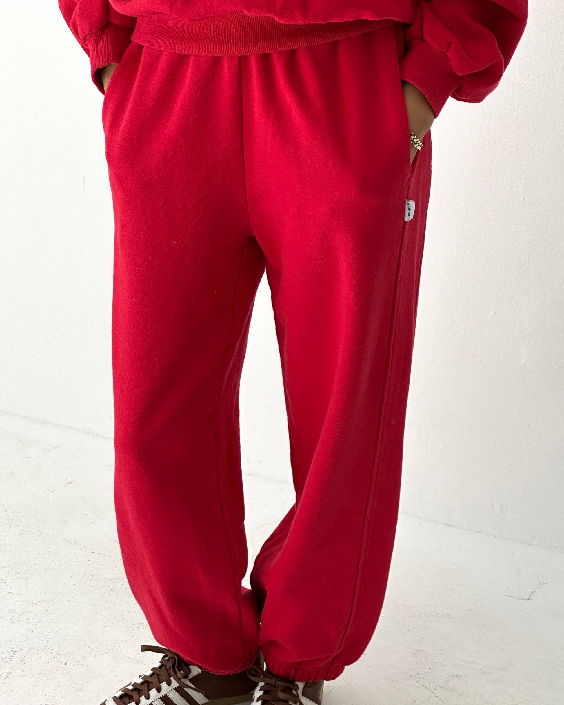 Person wearing a red tracksuit with brown shoes on a white background