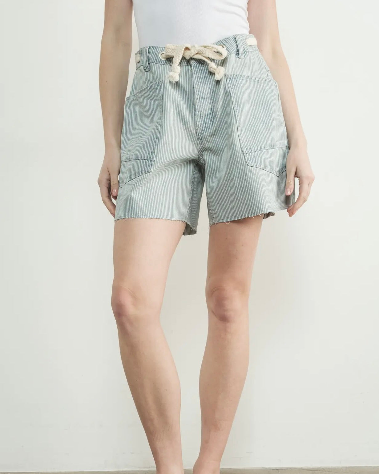Model is wearing Aaron and Amber Vintage Washed Barrel Denim Shorts with a white top on a white background