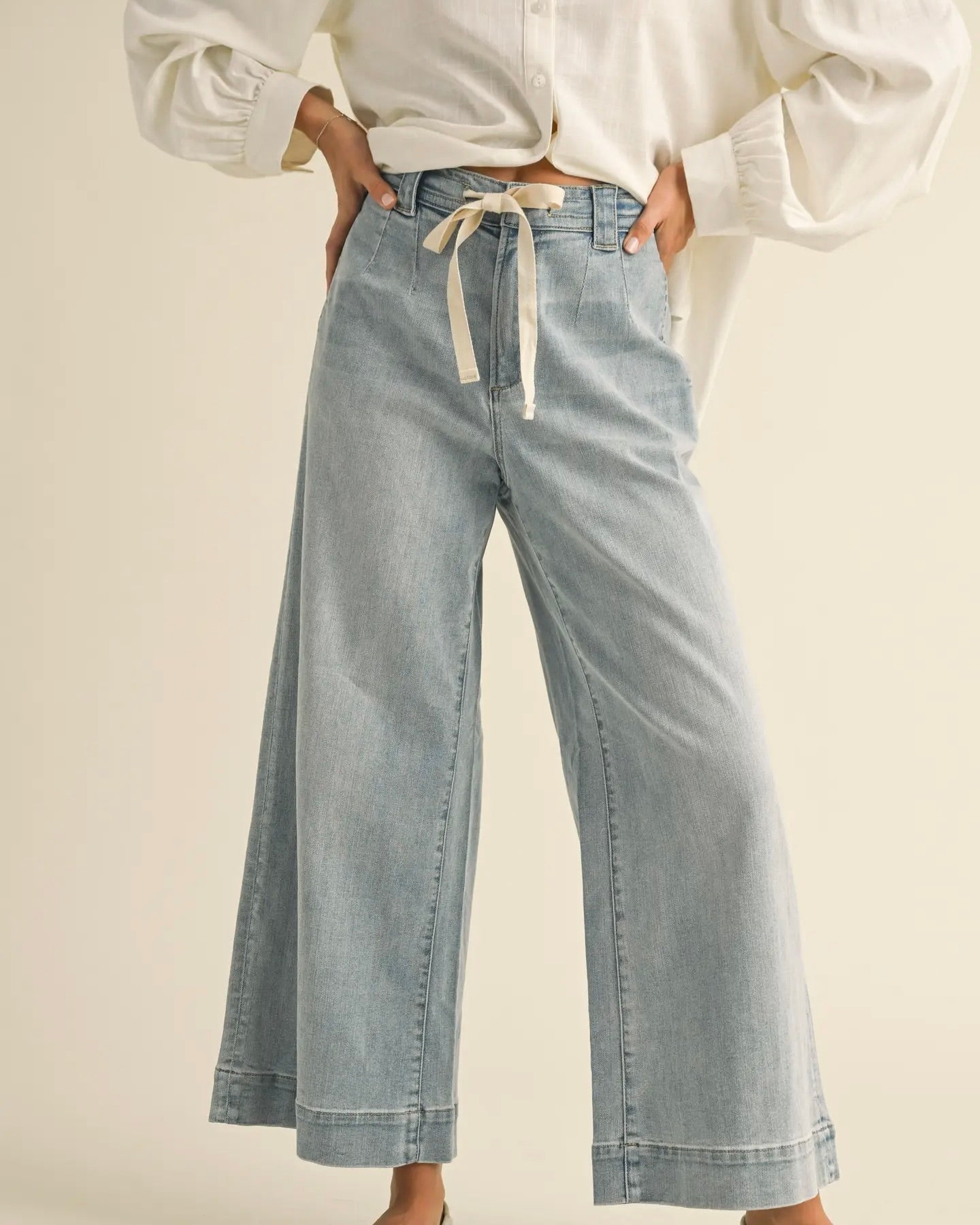 Model is wearing MIOU MUSE Washed Denim Tie Front Pants on a light beige background.