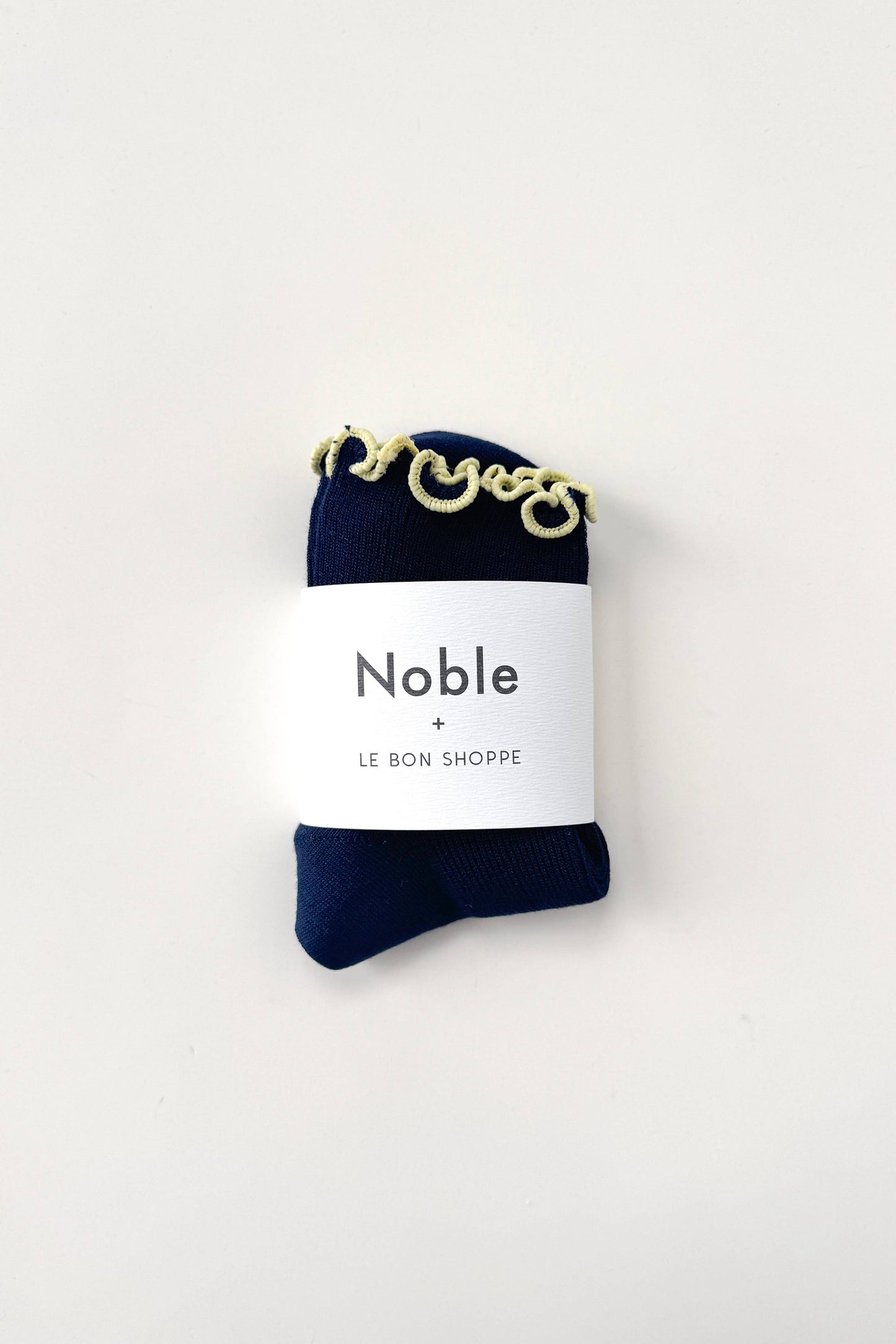 Navy blue sock with gold chain detail on a white label with 'Noble' branding.