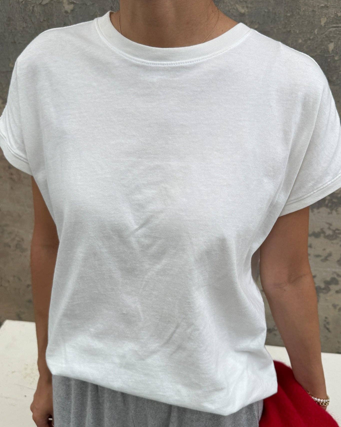 Person wearing a plain white t-shirt and gray pants against a neutral background