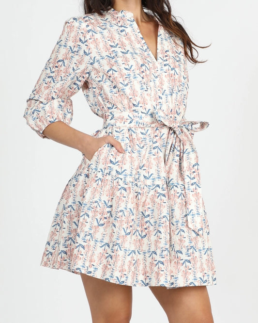 Front view of a model wearing the Greylin Marta belted dress with their hands in the pockets in front of a white background 