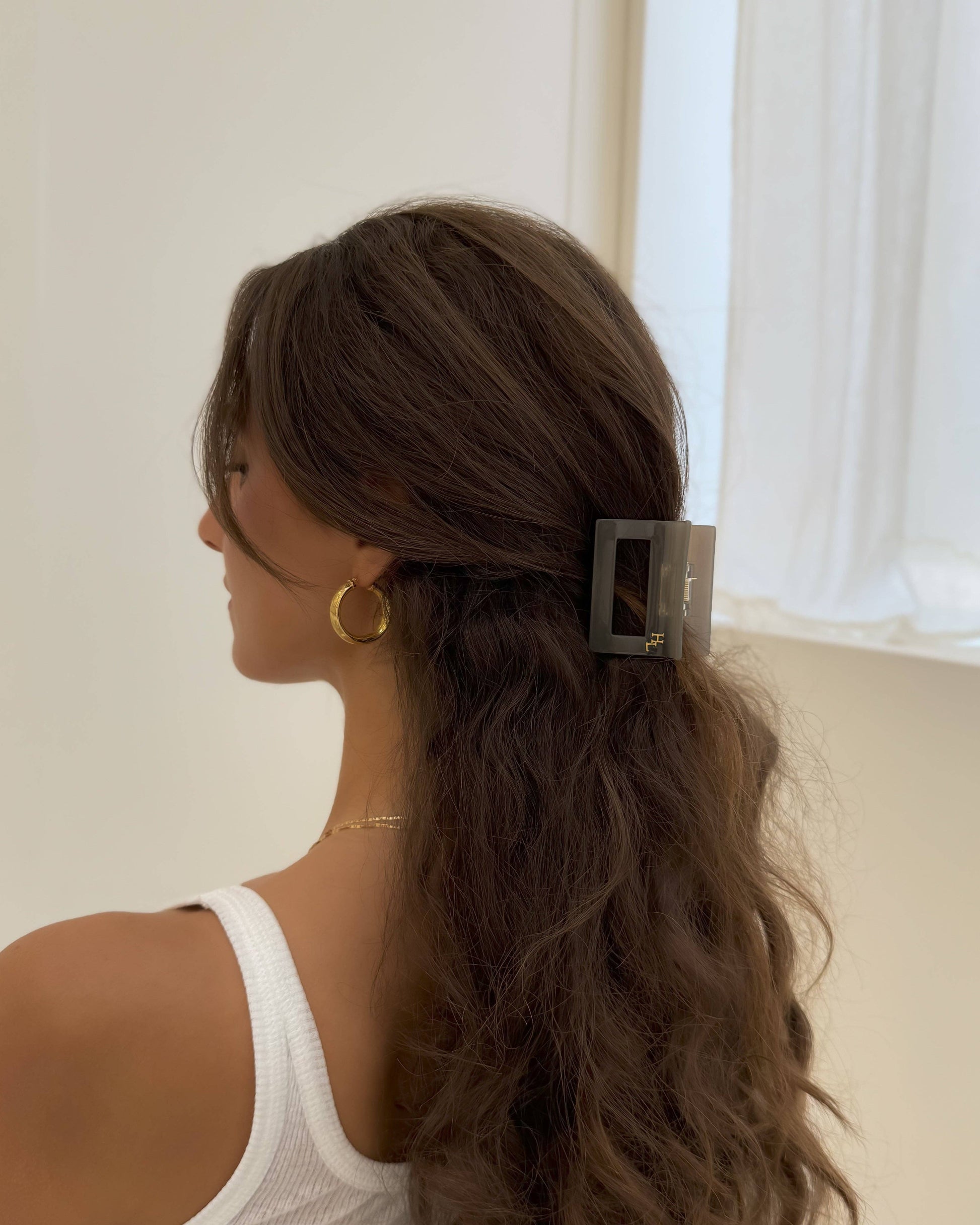 Woman with styled hair, wearing the HoneyLux Dolce Midi Acetate Claw clip in the color Capri Stonegold with a white top against a neutral background.