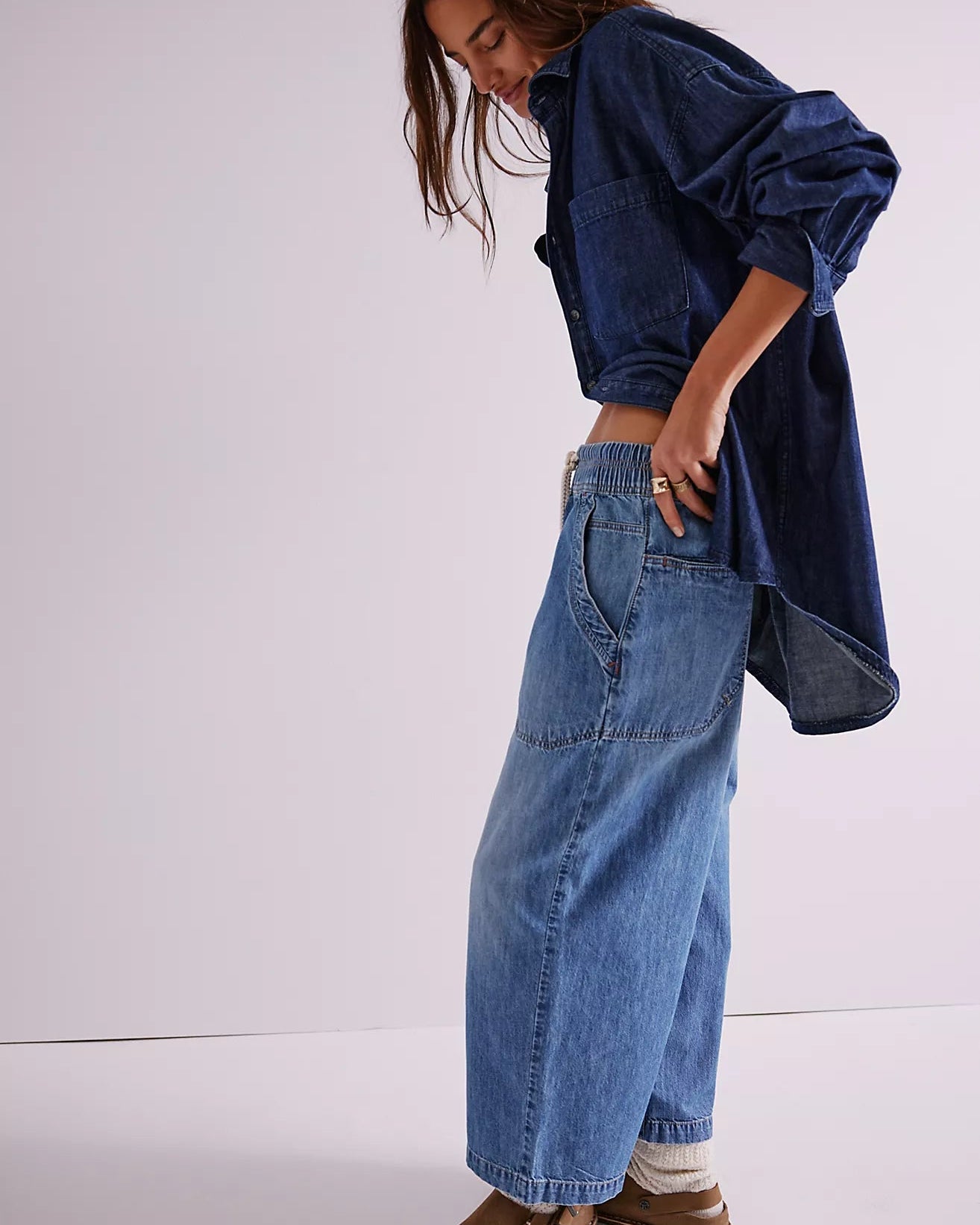 Person wearing a blue denim jacket and jeans on a white background
