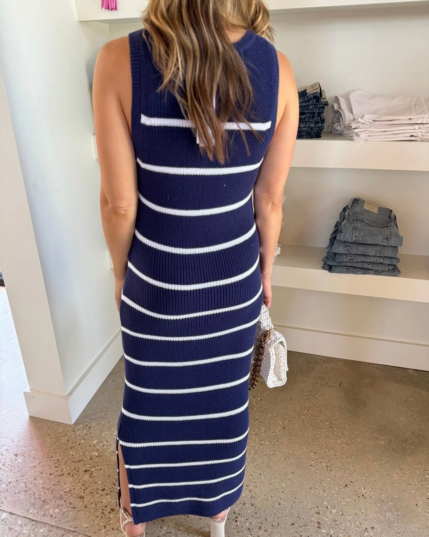 Model wearing 525 Emma Stripe Midi Dress holding a purse standing in front of jean rack