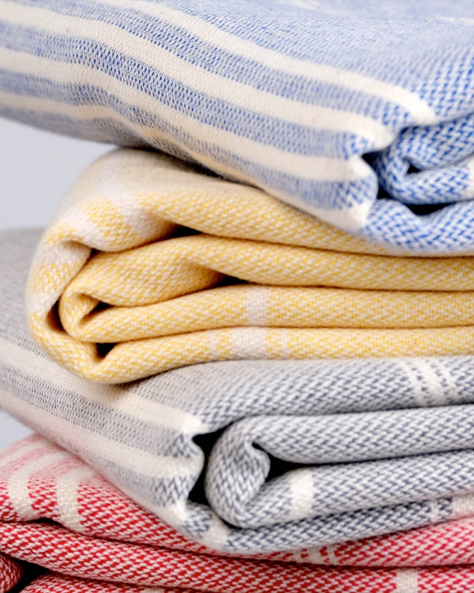 Stack of folded towels in various colors on a light gray background