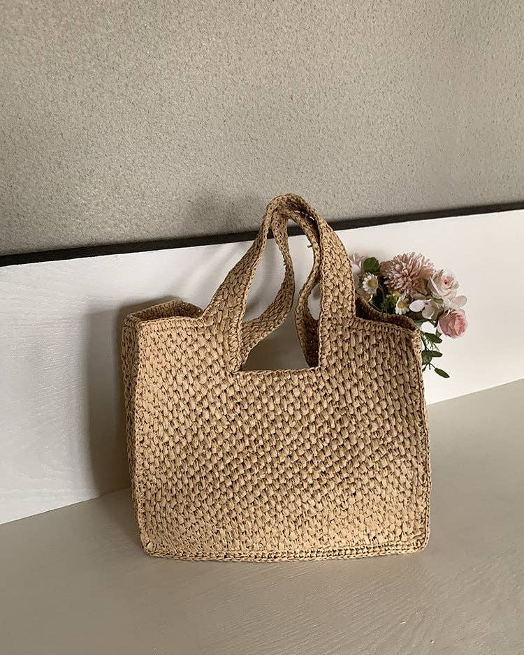 Woven beige handbag on a light surface with a neutral background