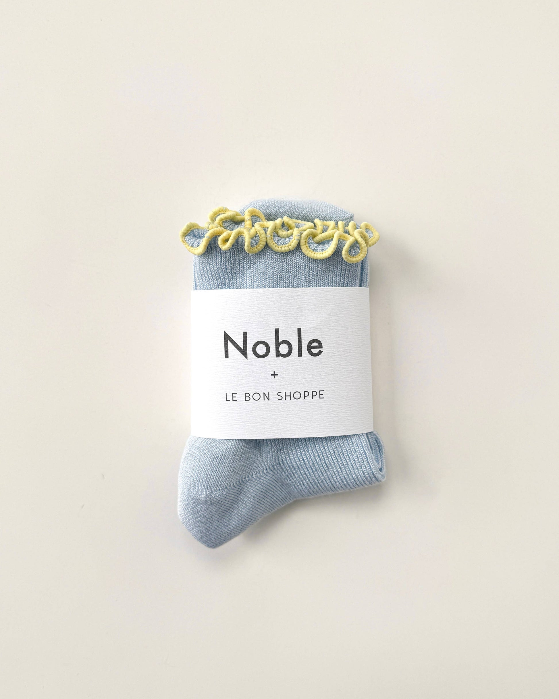 Blue socks with a 'Noble' label on a beige background