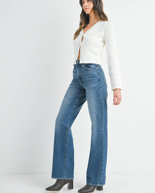 Woman wearing a white long-sleeve top and blue jeans on a white background