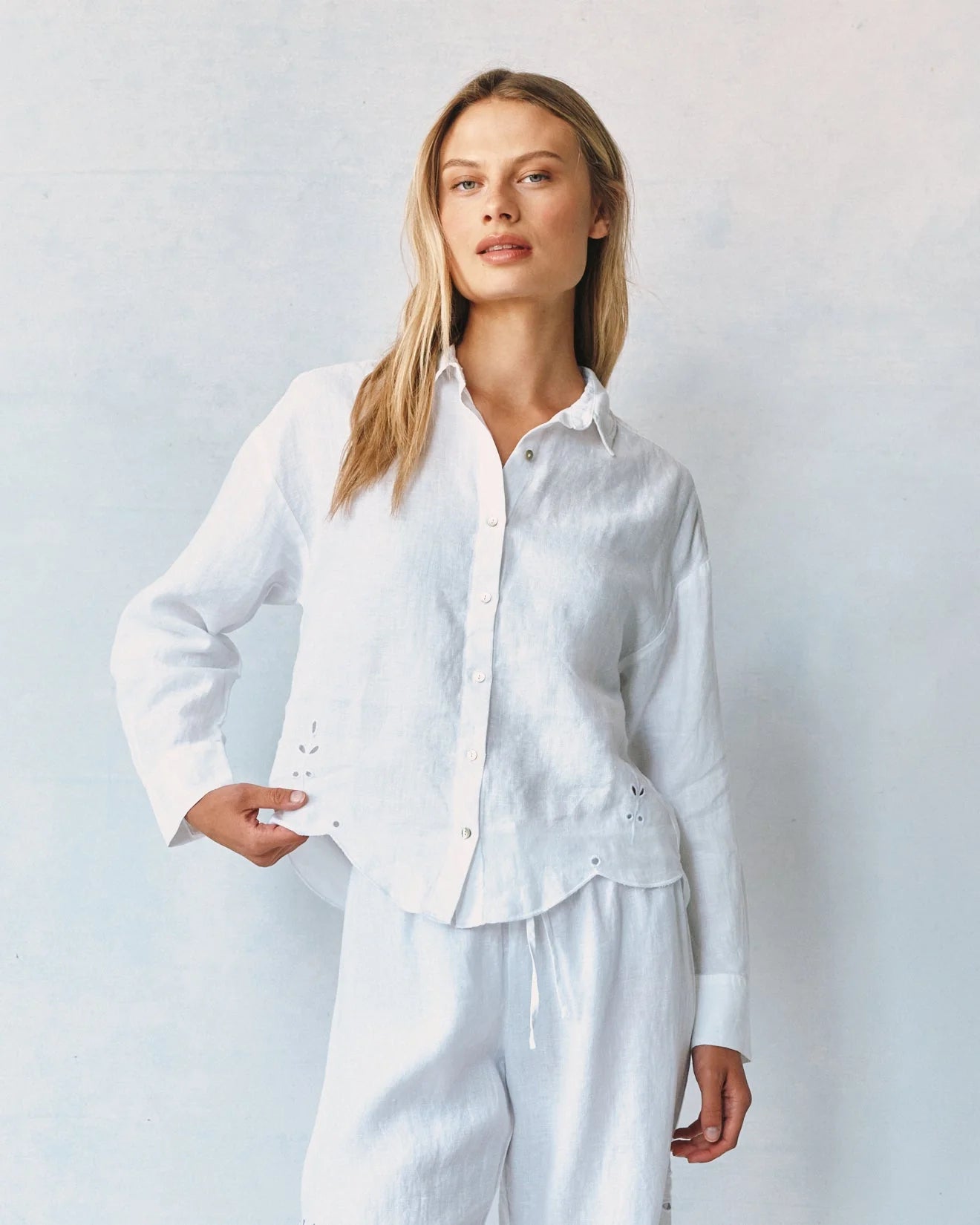 Woman wearing a white shirt and pants against a light gray background