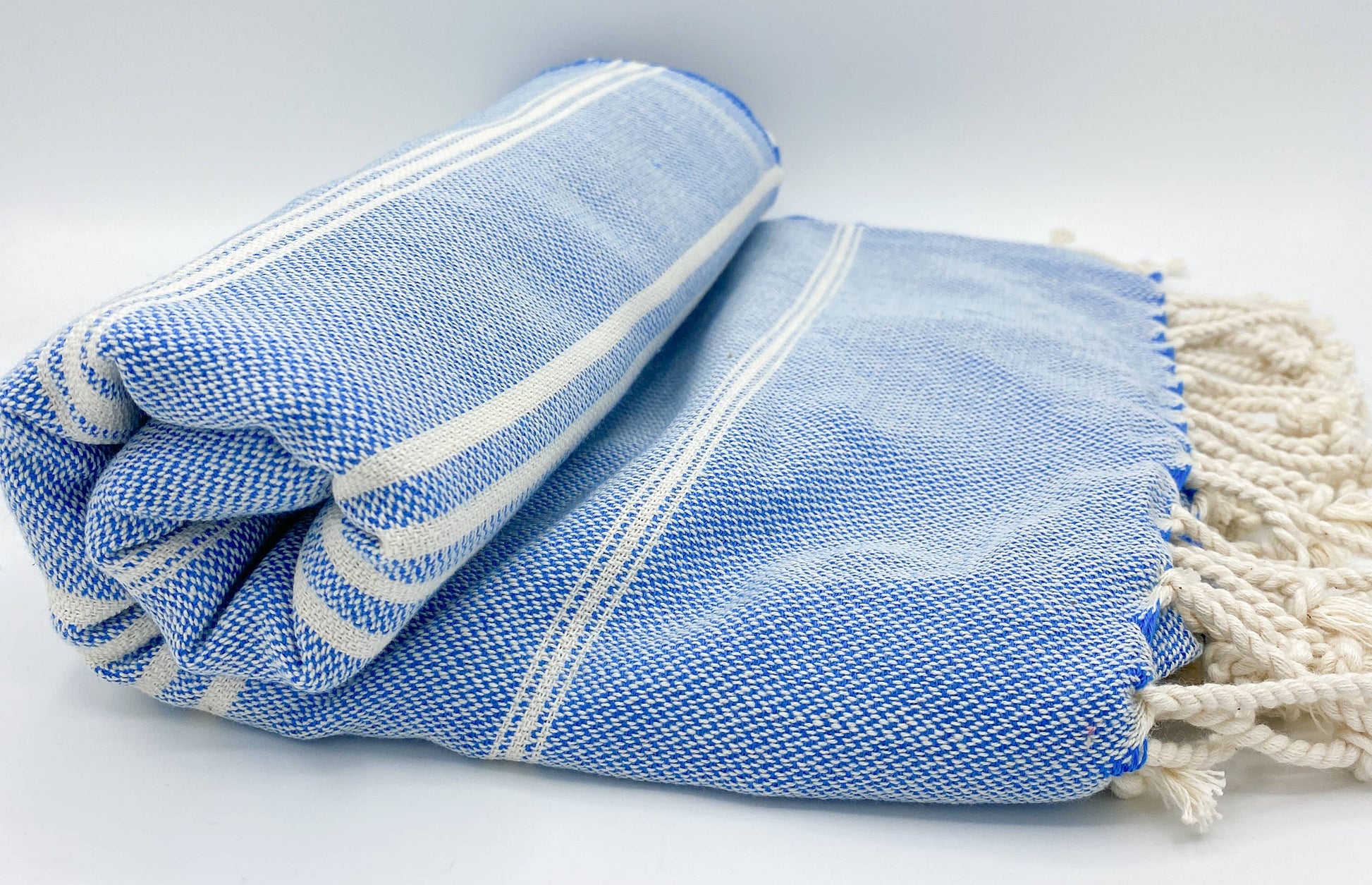 Blue and white patterned towel with tassels on a light gray background