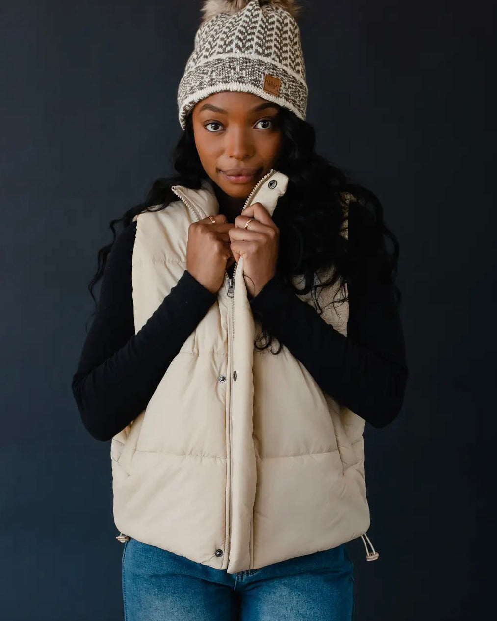 Model wearing Panache Tan puffer vest wearing black shirt and jeans on a black background