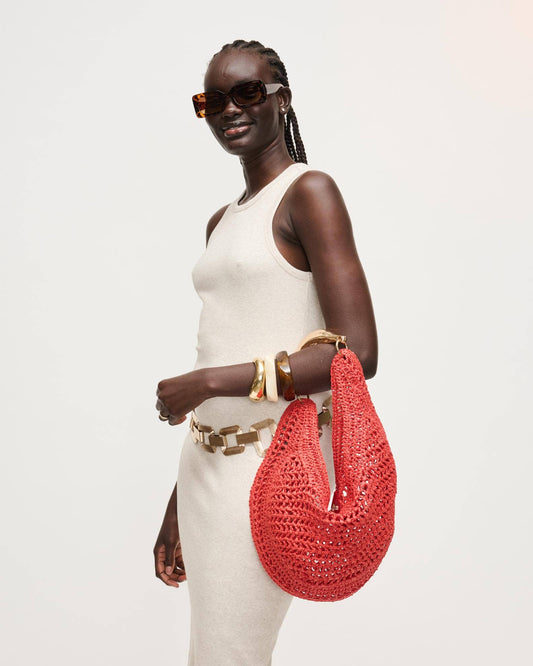 Woman holding a red woven handbag against a white background