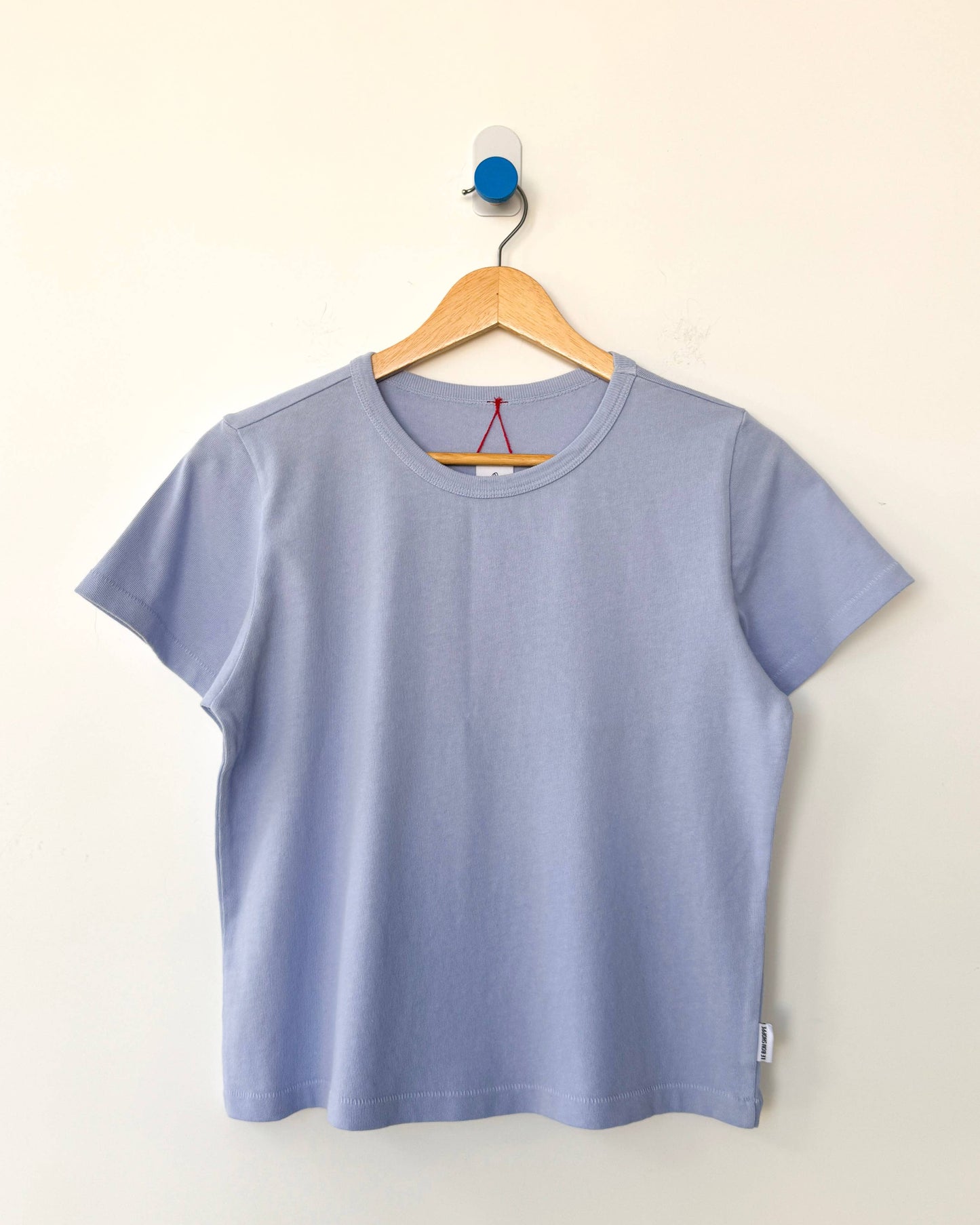 Light blue t-shirt on a wooden hanger against a white background