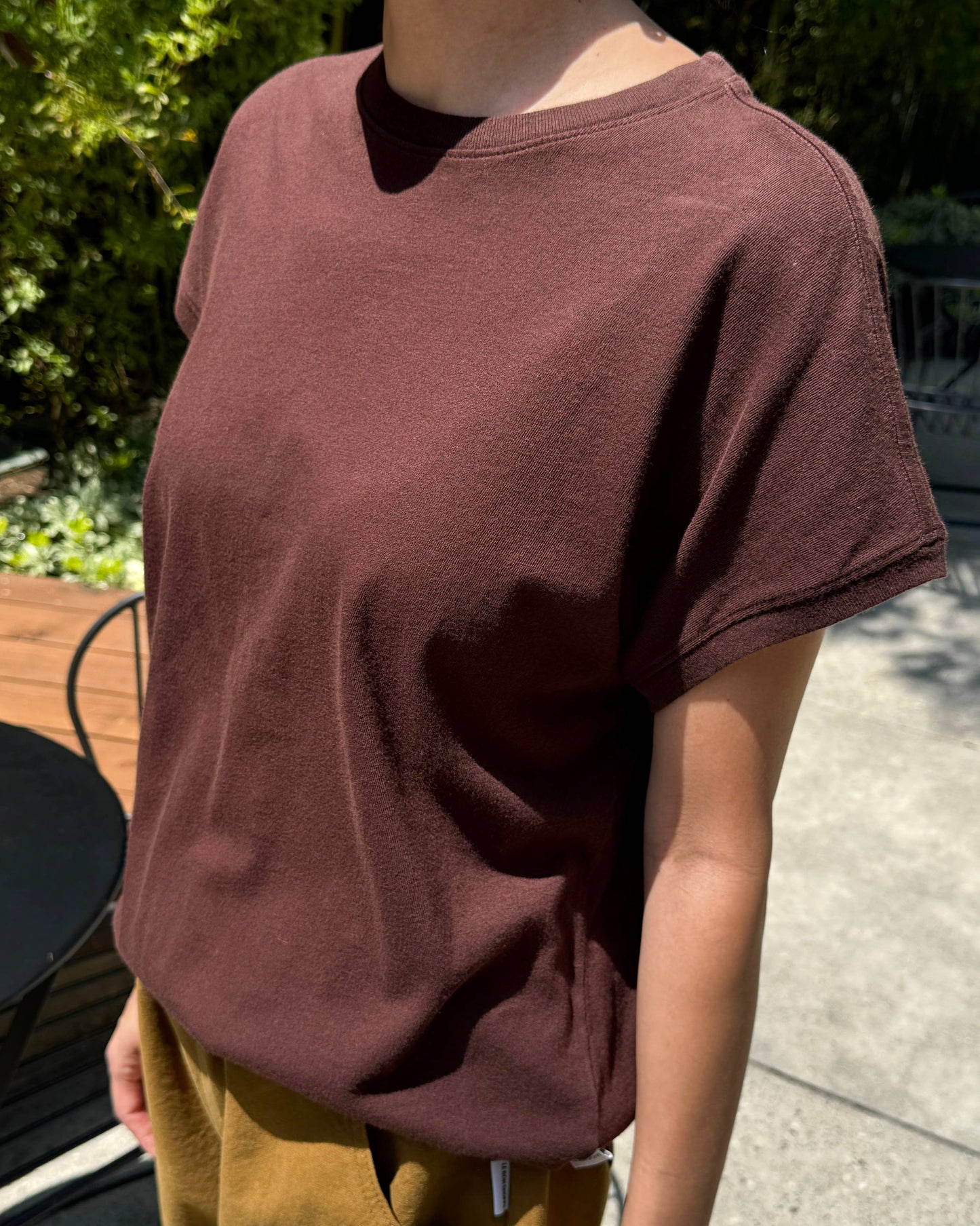 Person wearing a brown t-shirt and mustard pants outdoors