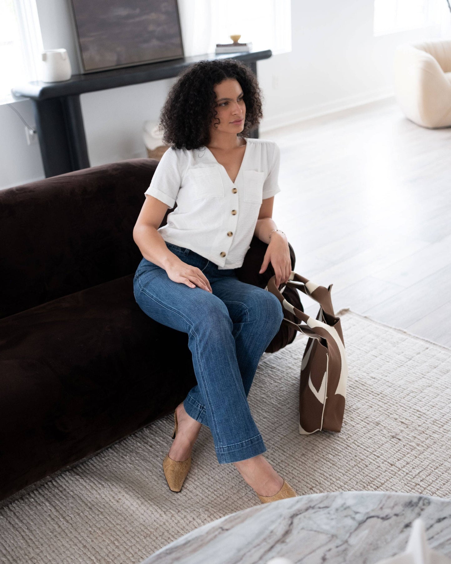 Woman sitting on a brown couch in a modern living room.