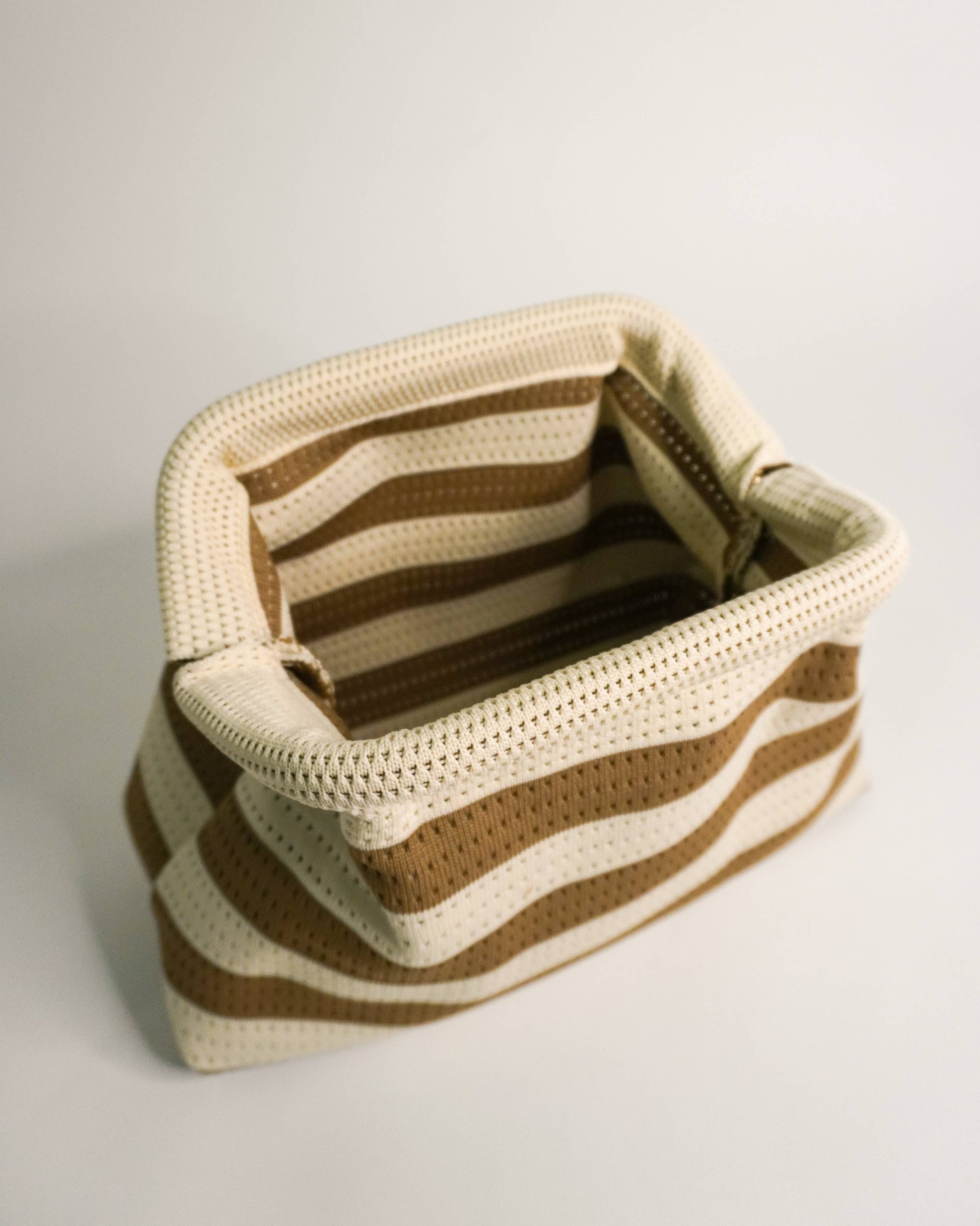 Crocheted basket with brown and beige stripes on a light gray background
