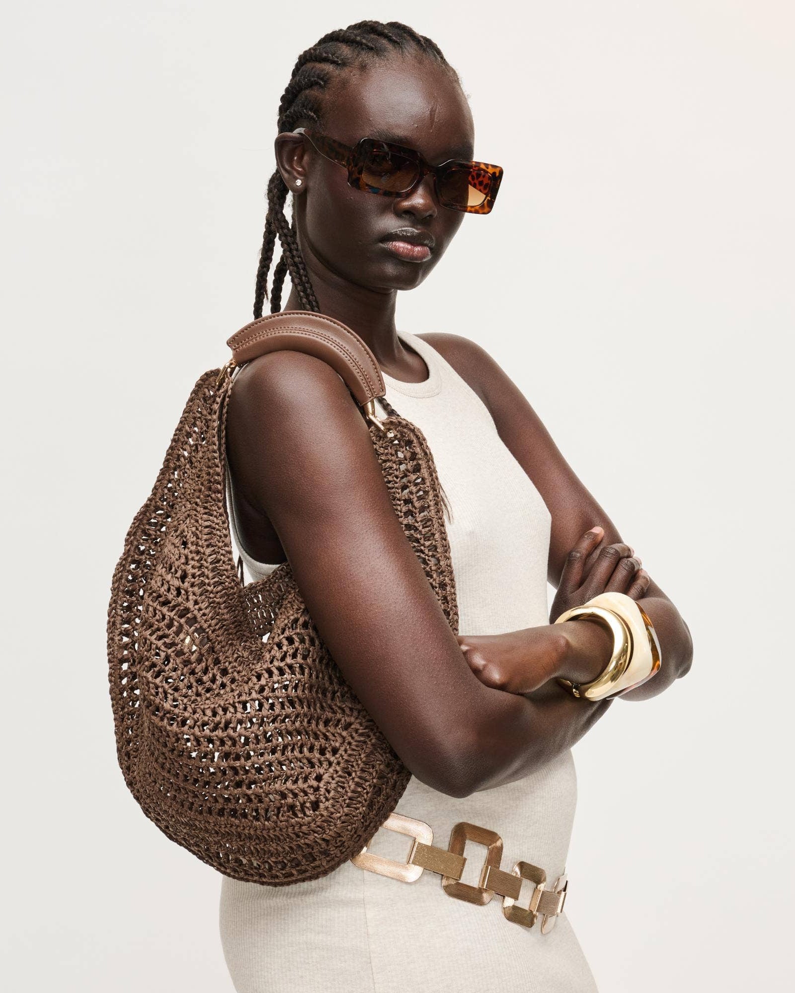 Woman holding a brown woven handbag against a white background