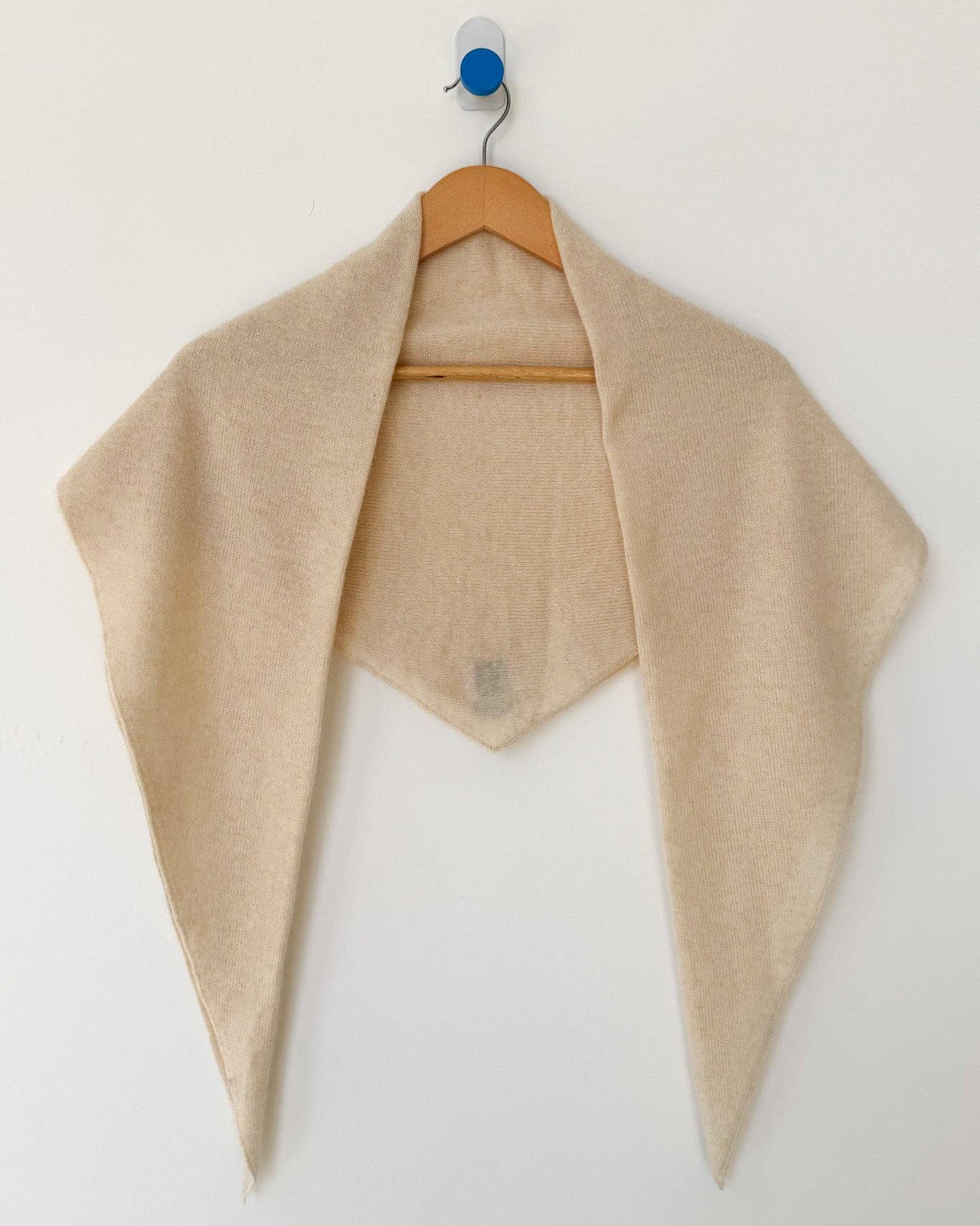 Beige shawl draped over a hanger against a white background
