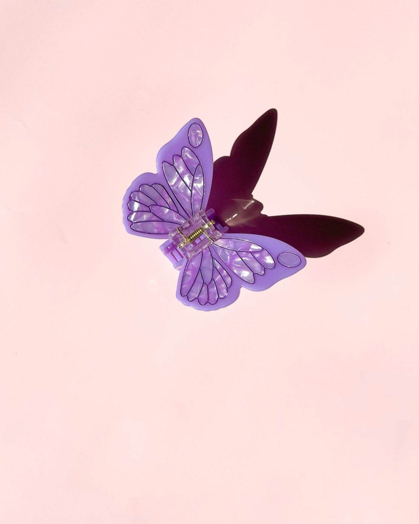 Purple butterfly hair clip on a pink background