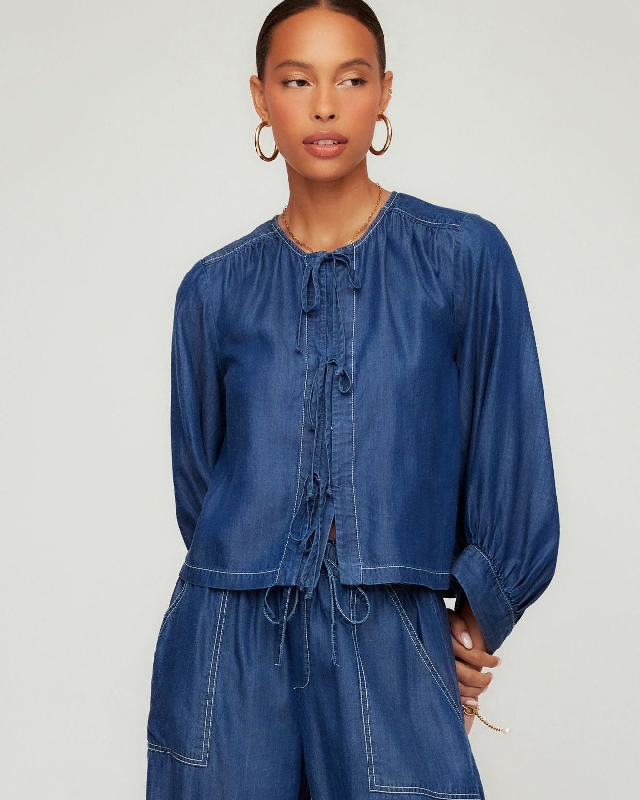 Woman wearing a blue denim outfit on a plain background