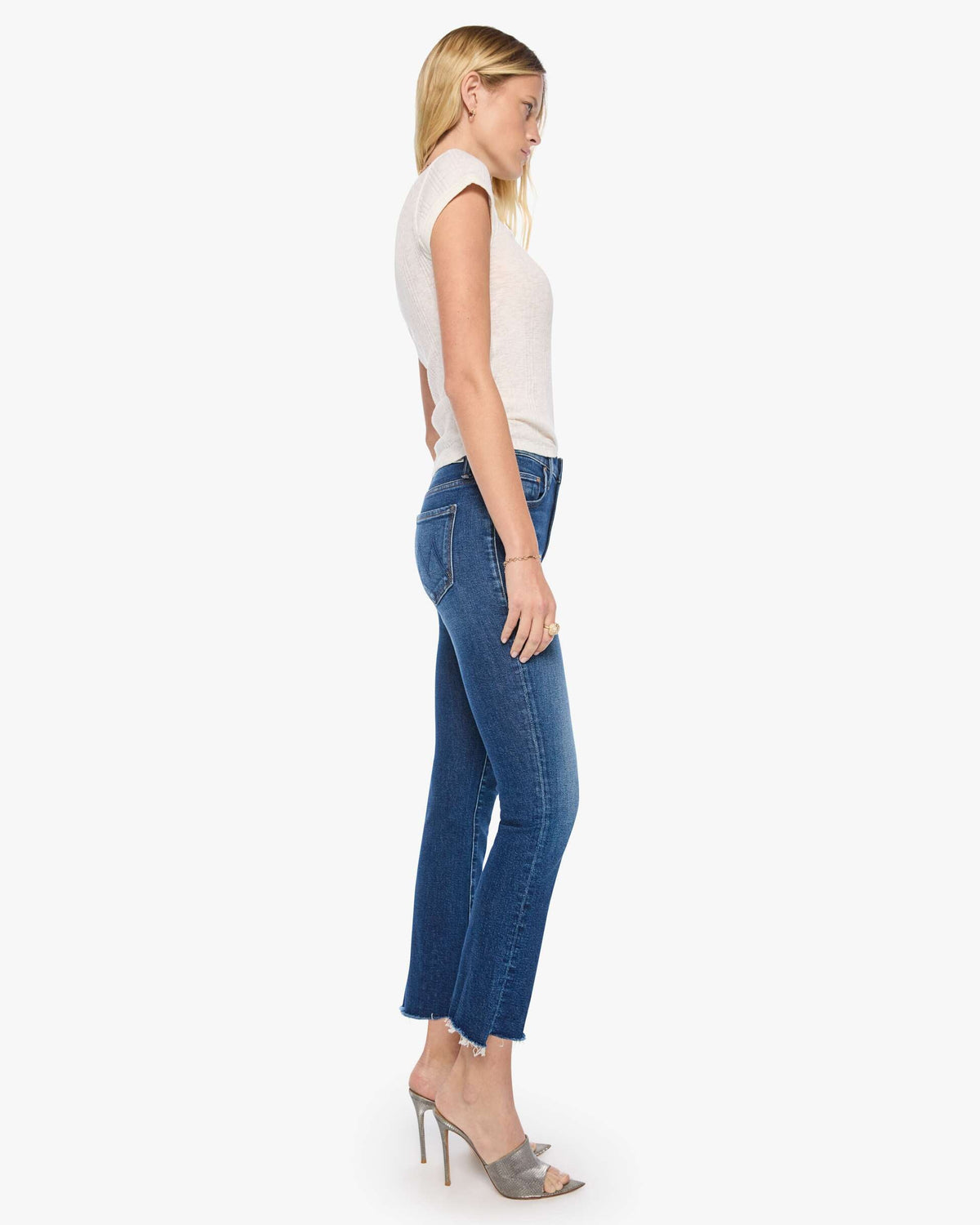 Woman wearing a white top and blue jeans on a white background