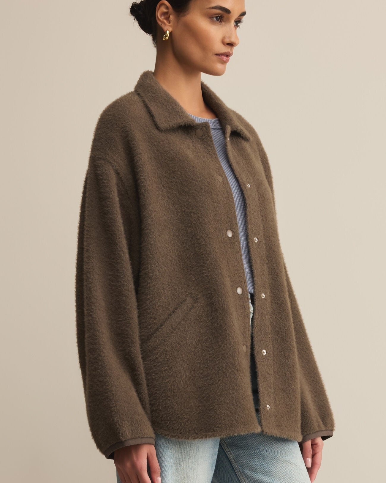 Woman wearing a brown coat against a beige background
