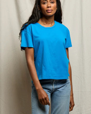Woman wearing a blue t-shirt and jeans against a plain background