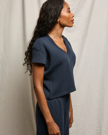 Woman wearing a navy blue outfit against a plain background