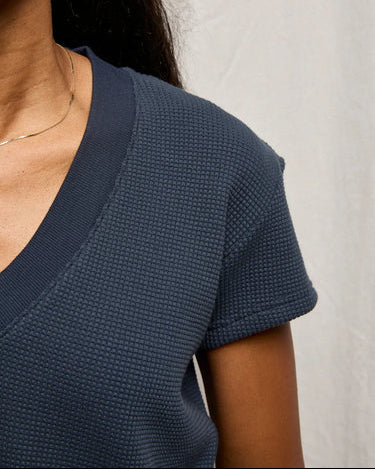 Navy textured short-sleeve top worn by a person against a neutral background