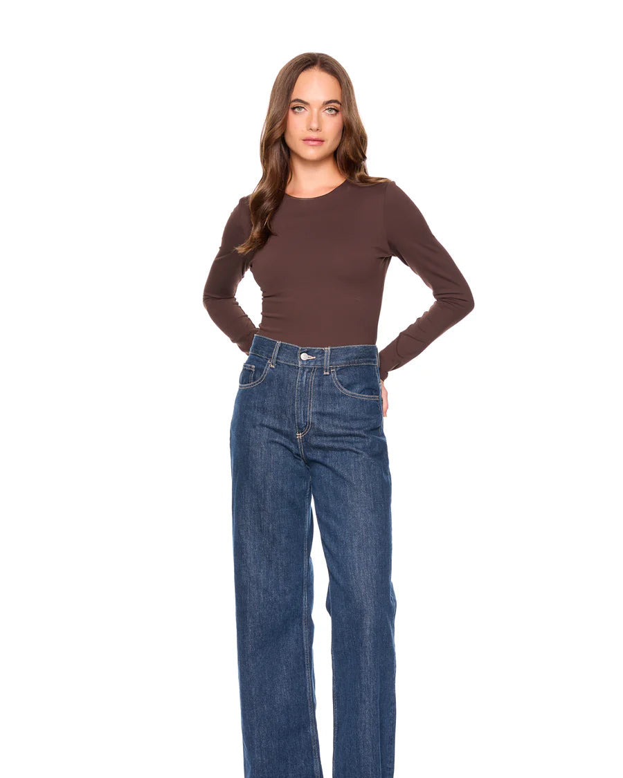 Woman wearing a brown top and blue jeans on a white background