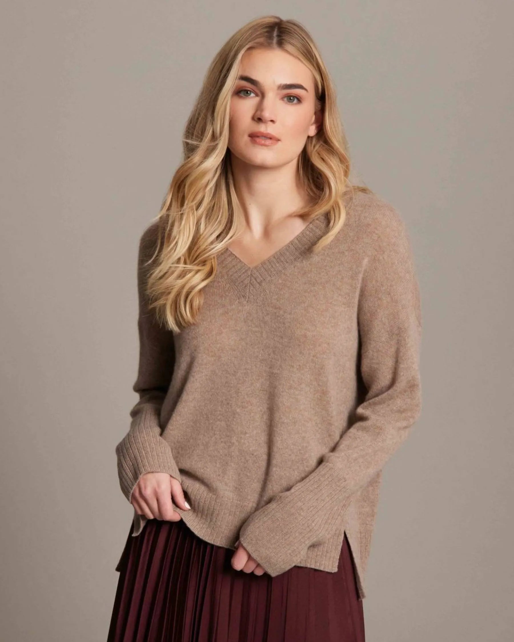 Woman wearing a brown sweater against a plain background