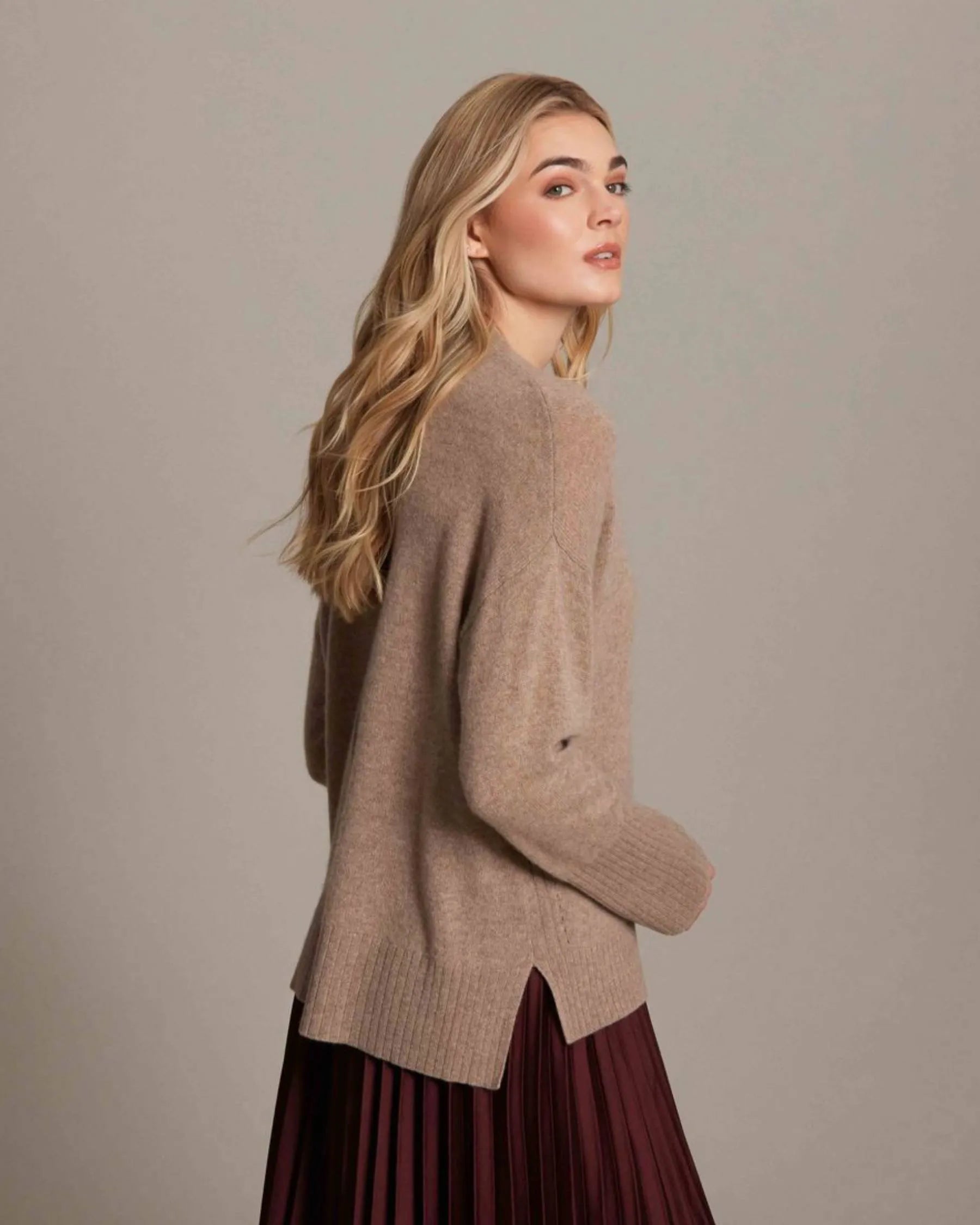 Woman wearing a brown sweater against a plain background