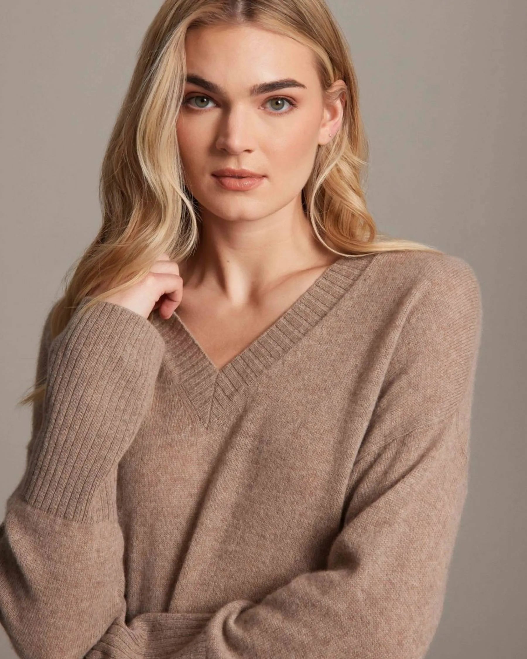 Woman wearing a brown sweater against a neutral background