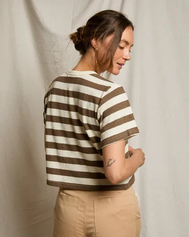 Person wearing a striped shirt and beige pants against a plain background