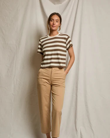 Woman wearing a striped shirt and beige pants against a plain background