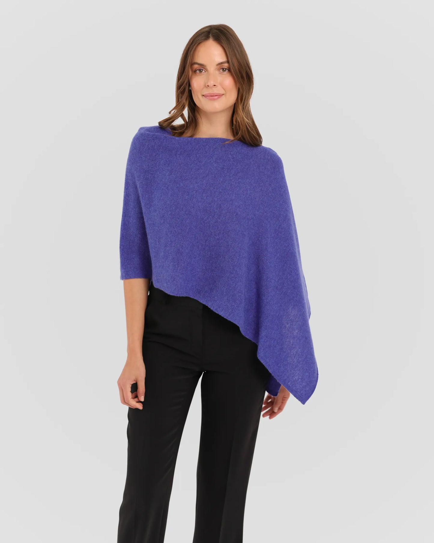 Woman wearing a blue poncho over a black outfit on a white background