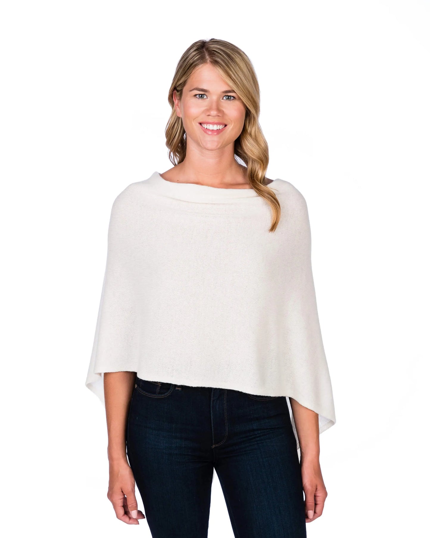 Woman wearing a white poncho over a dark outfit on a white background