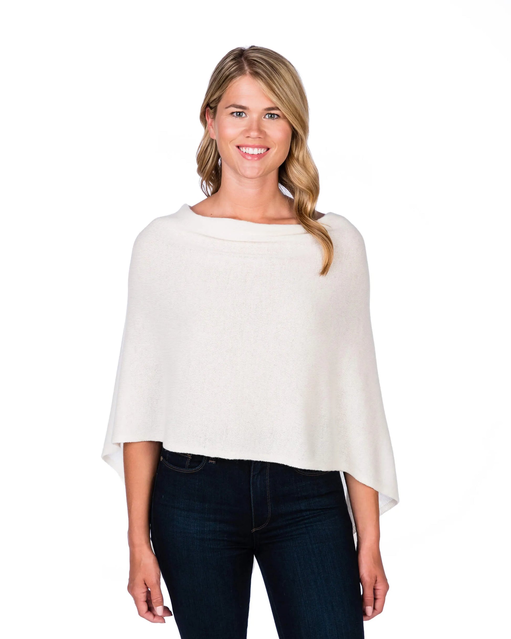 Woman wearing a white poncho over a dark outfit on a white background