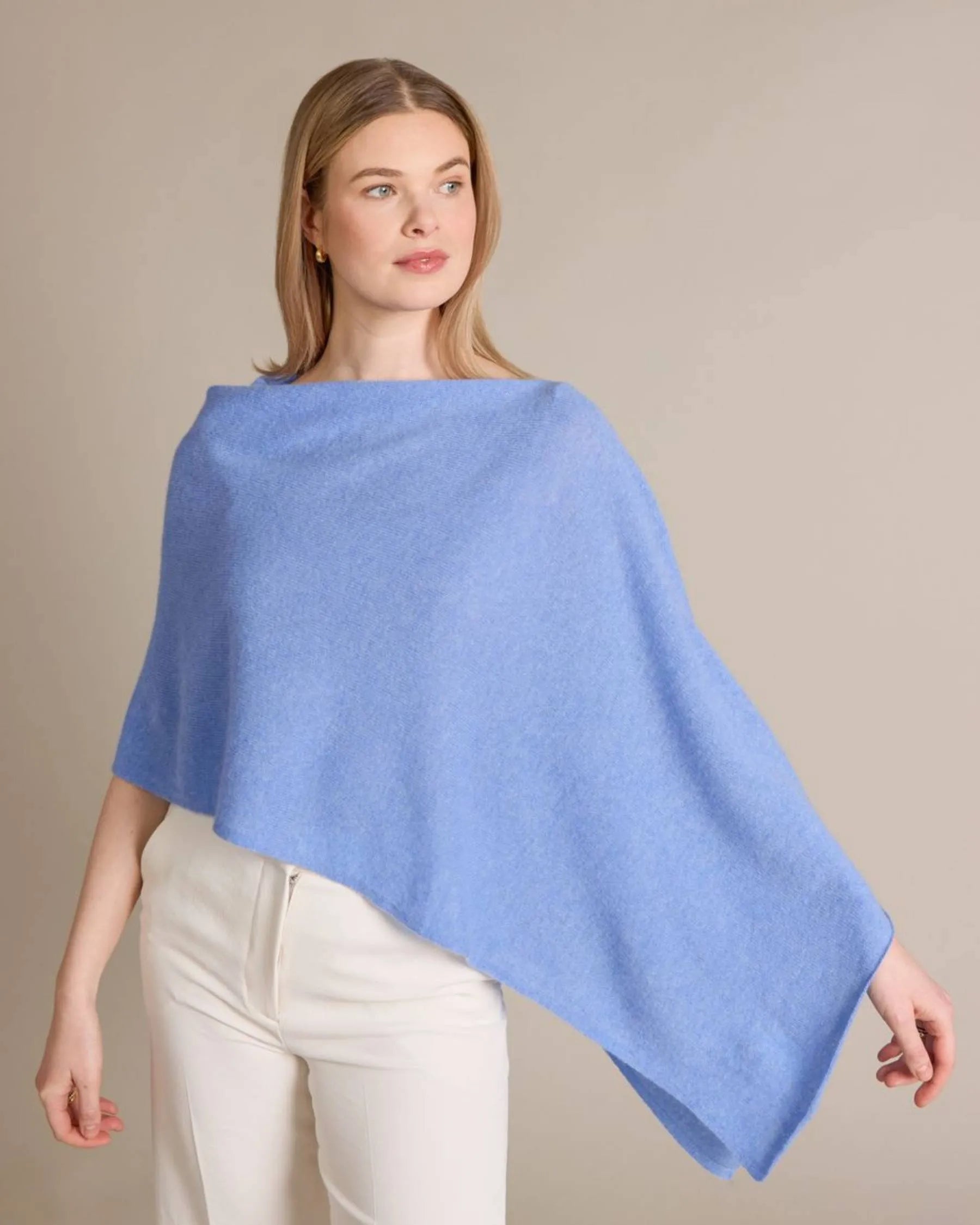 Woman wearing a light blue poncho against a beige background
