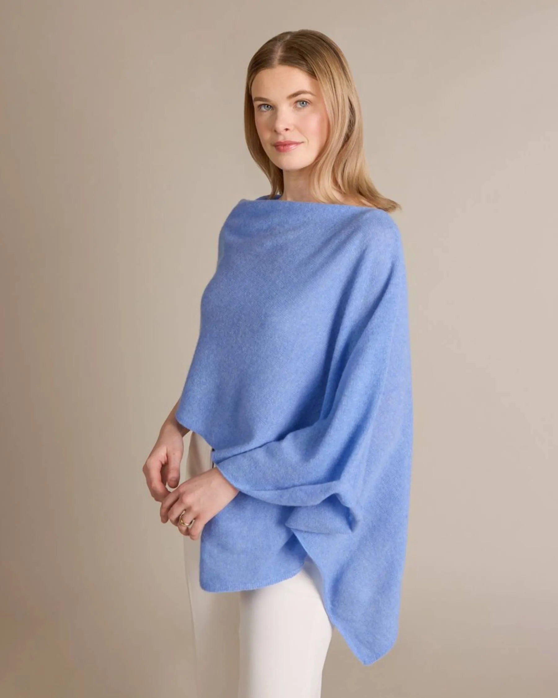 Woman wearing a blue poncho against a beige background