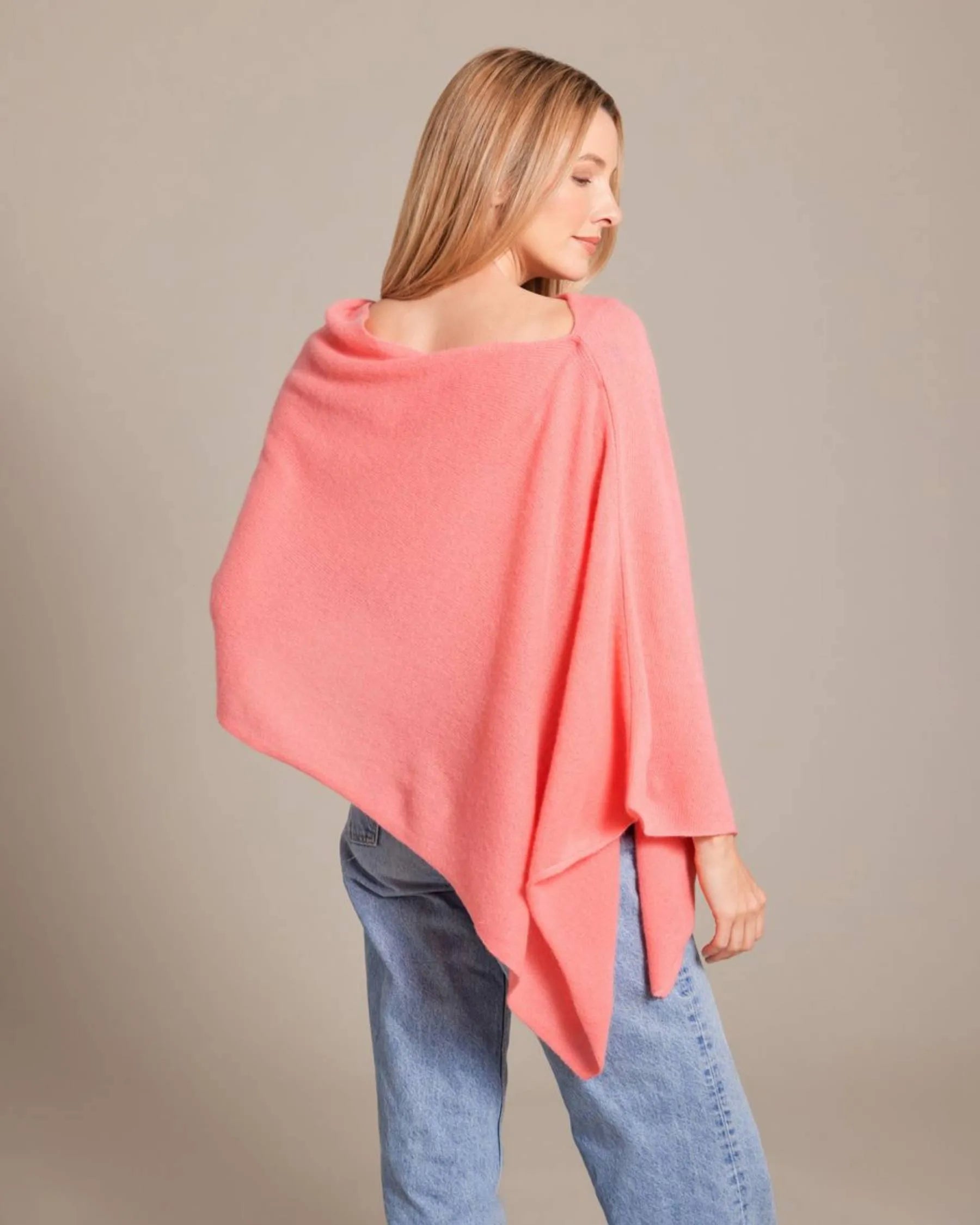 Woman wearing a pink poncho over a beige background