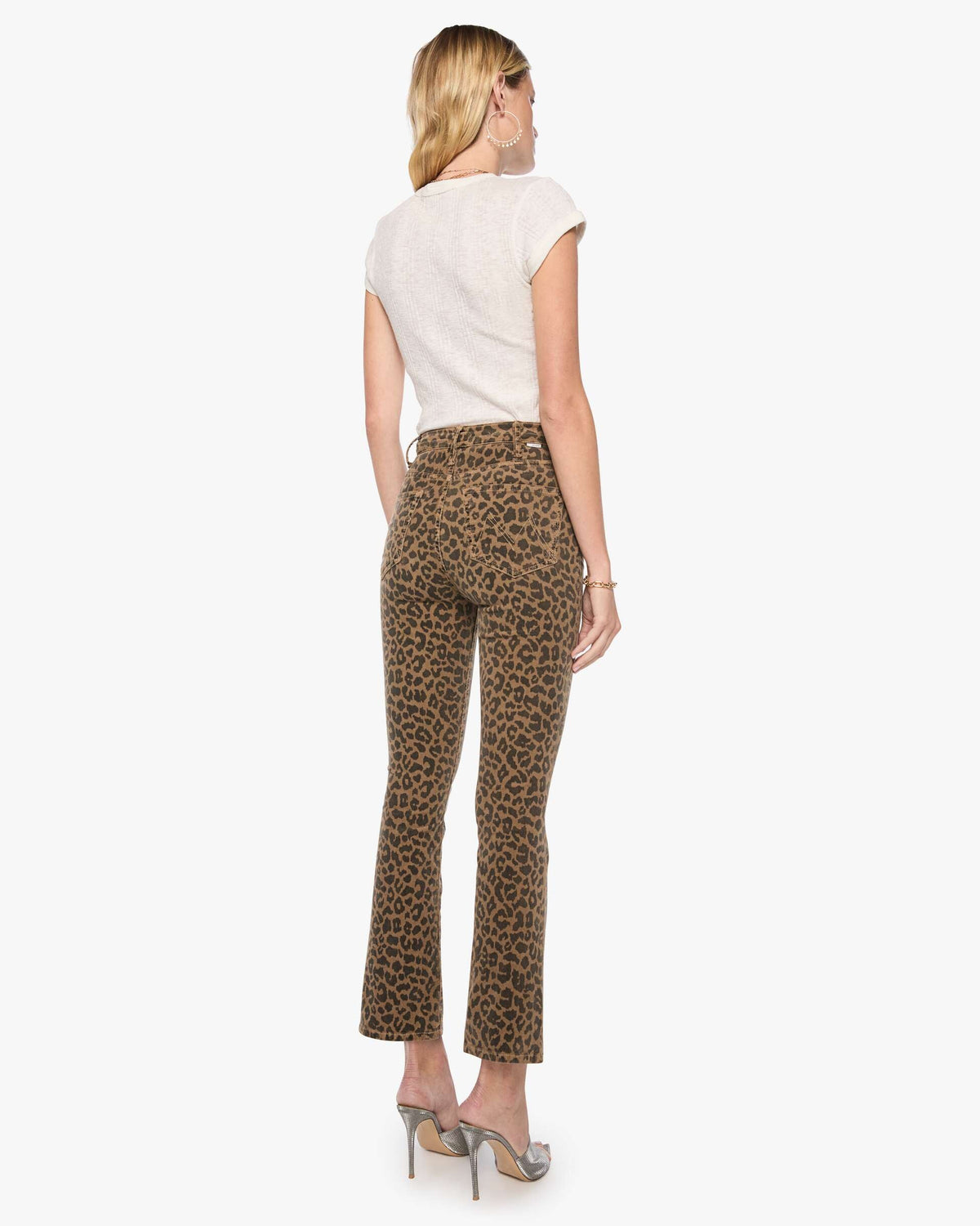 Woman wearing leopard print pants and a white top on a white background