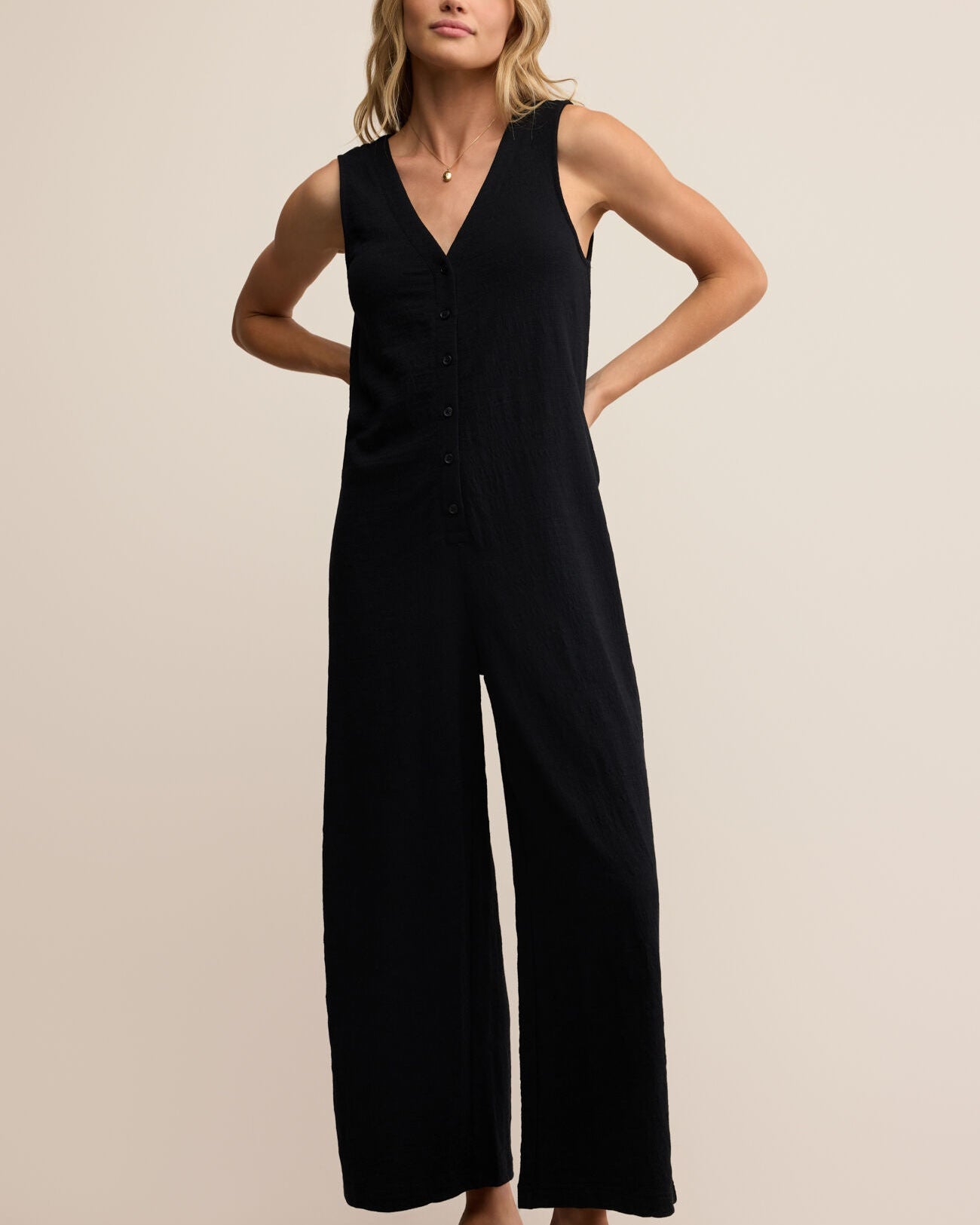 Woman wearing a black jumpsuit on a beige background
