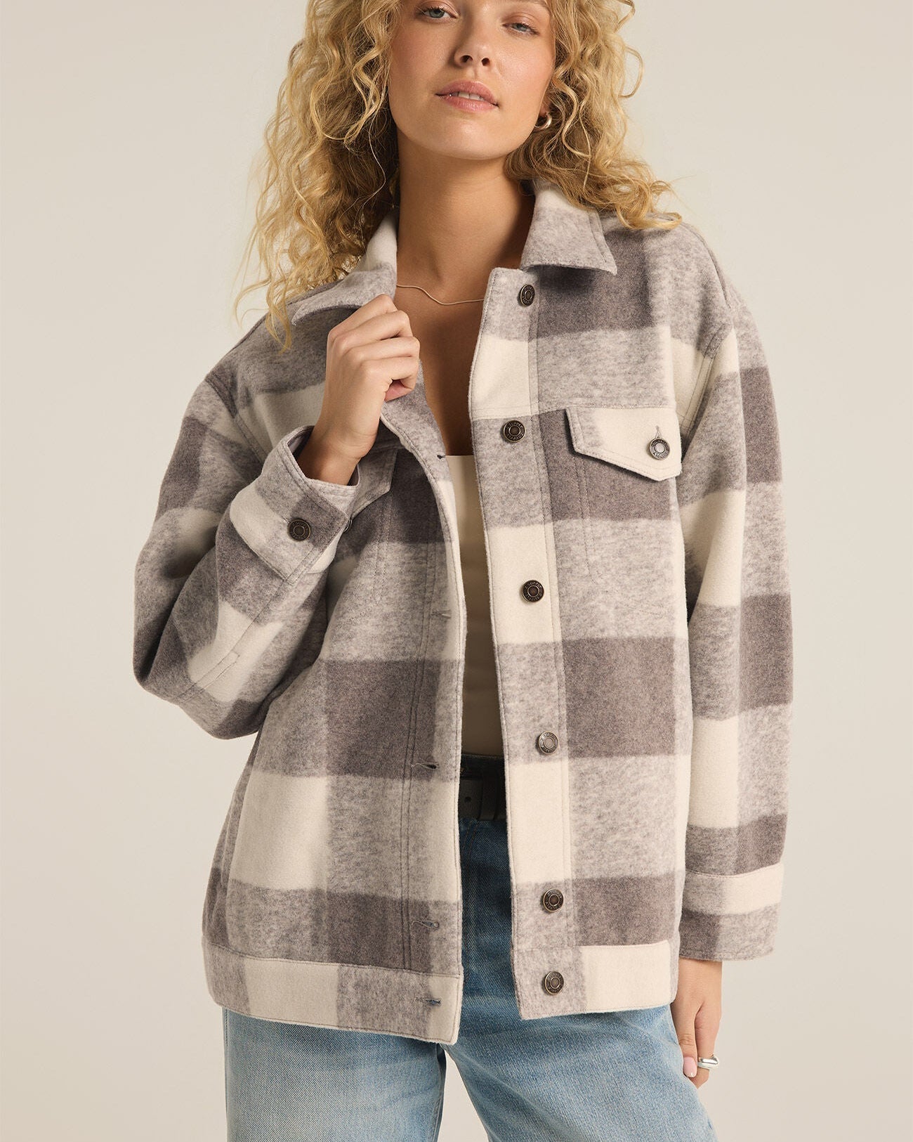 Model wearing Z SUPPLY Preston Knit Plaid Jacket in Slate Grey wearing jeans on a beige background 