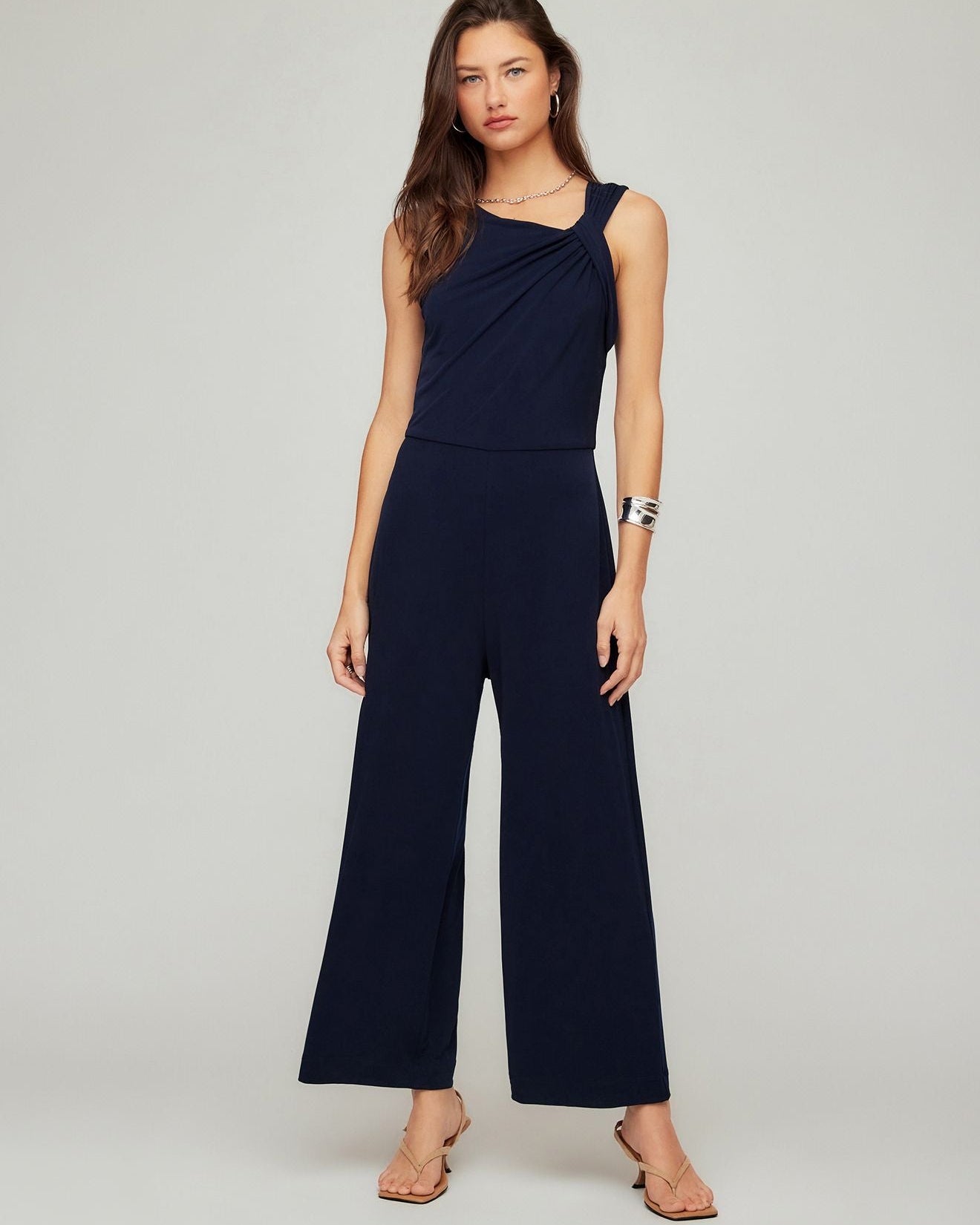 Woman wearing a navy blue jumpsuit on a gray background