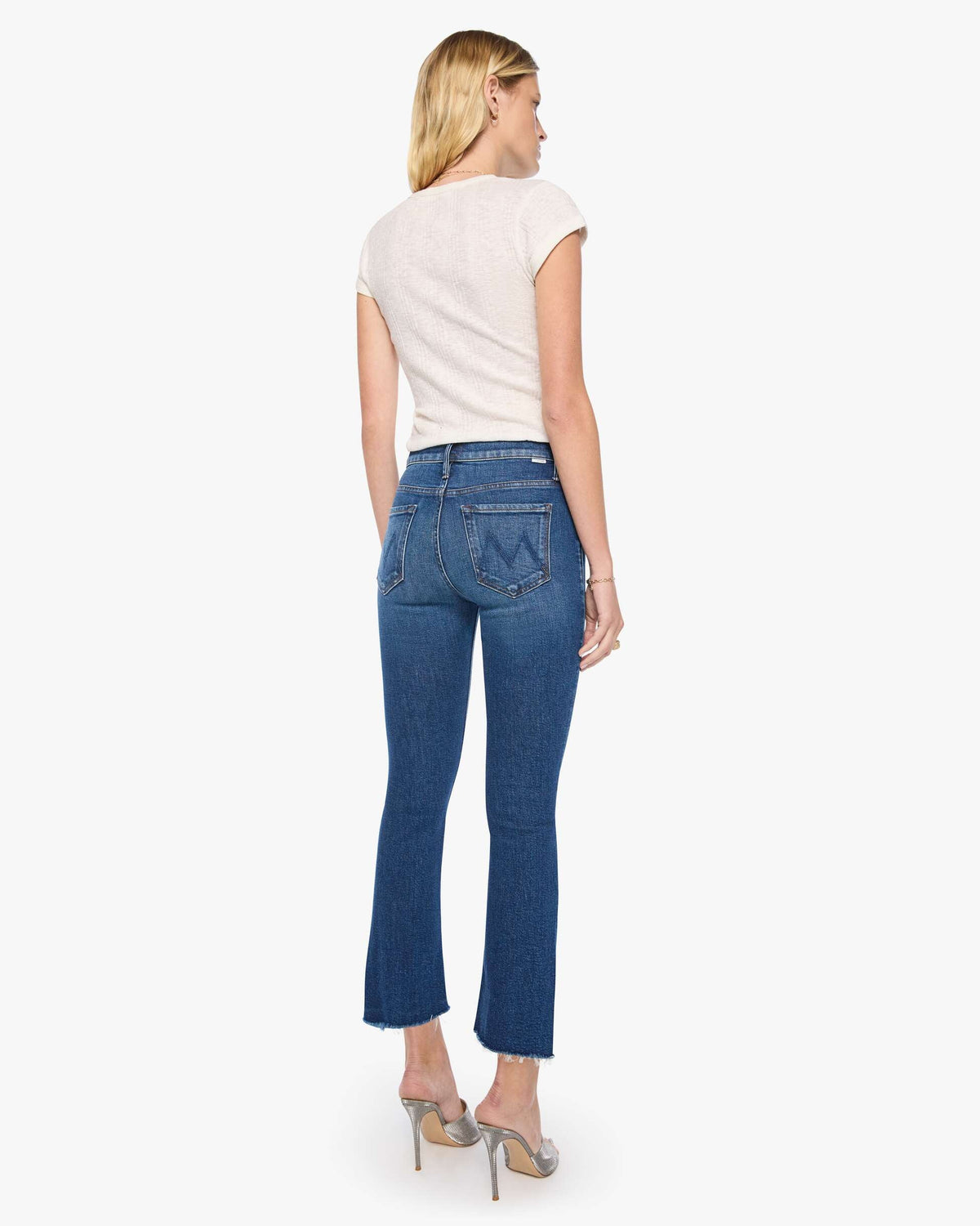Woman wearing blue jeans and a white top on a white background