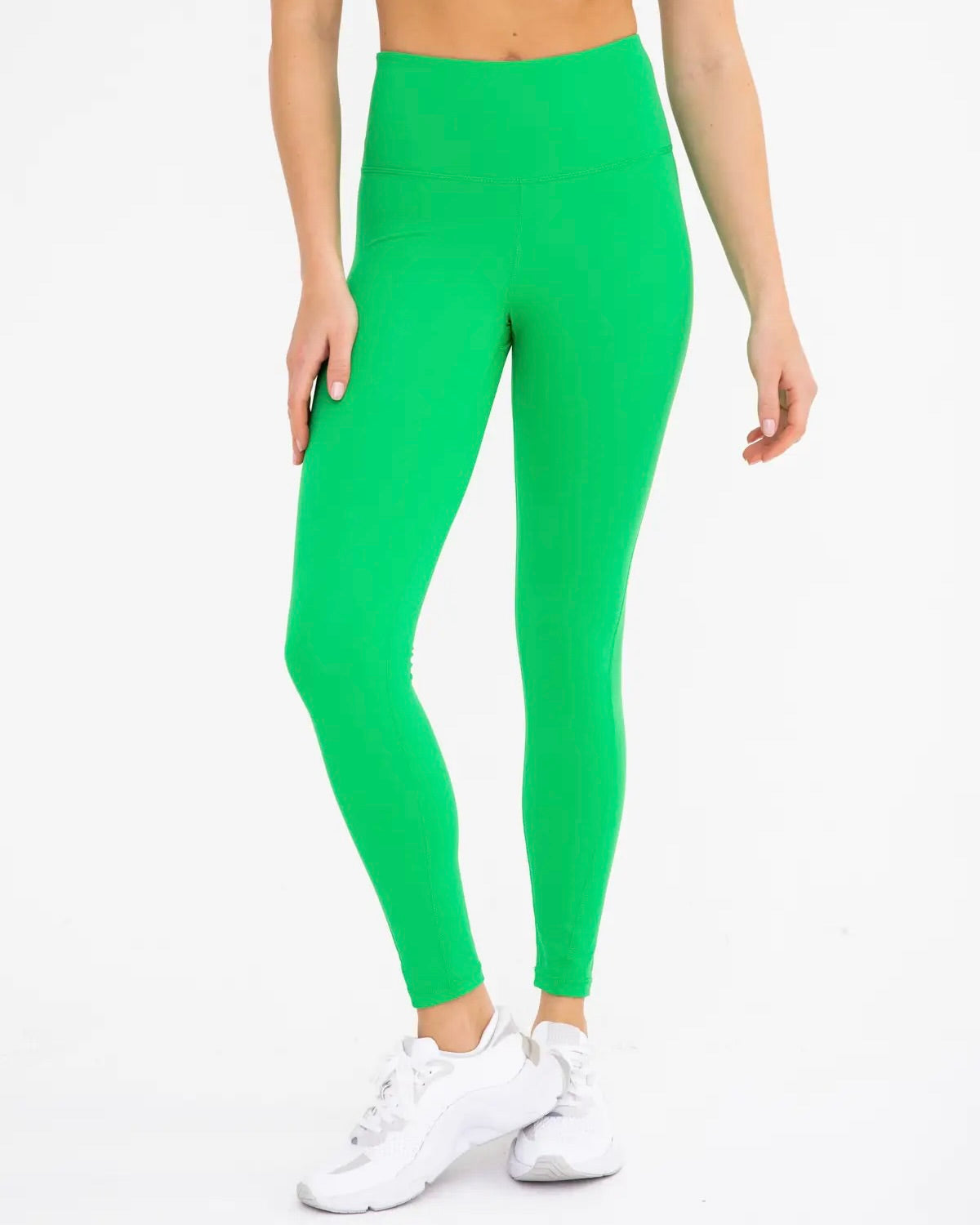 Model only showing legs wearing apple green leggings wearing white sneakers on a white background 
